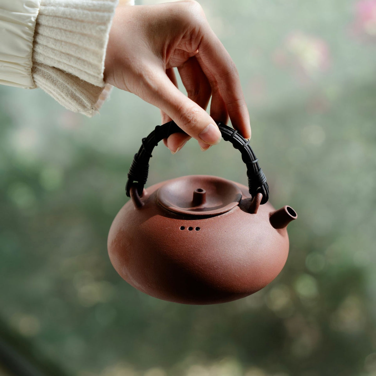Rattan handle clay boiling teapot 420ml held up by its overhead handle