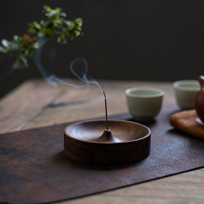 Walnut incense holder in use on a tea table beside cups