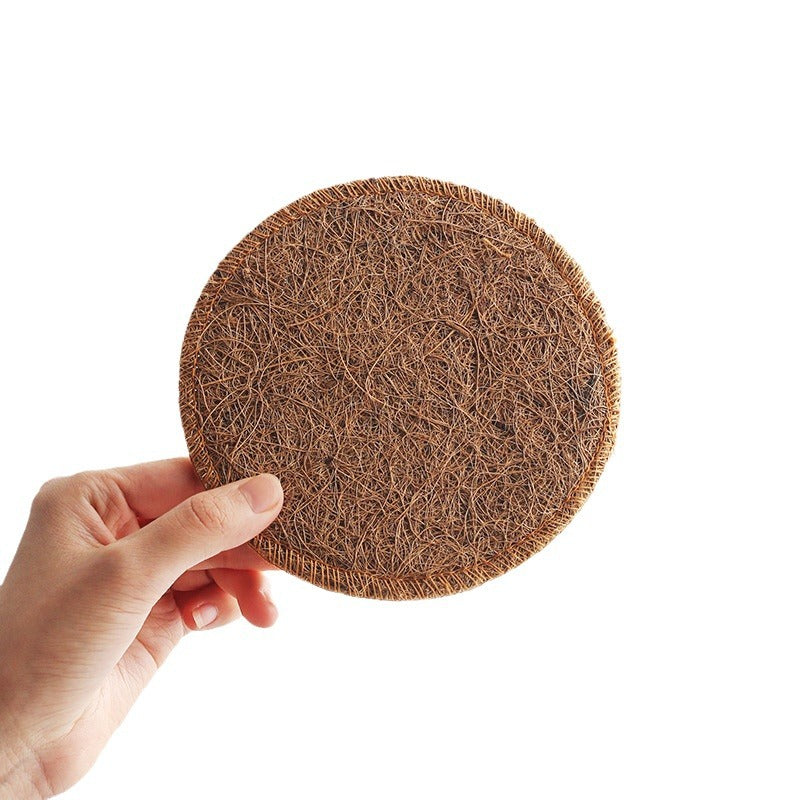 Round loofah tea coaster 8cm held in hand on a white background