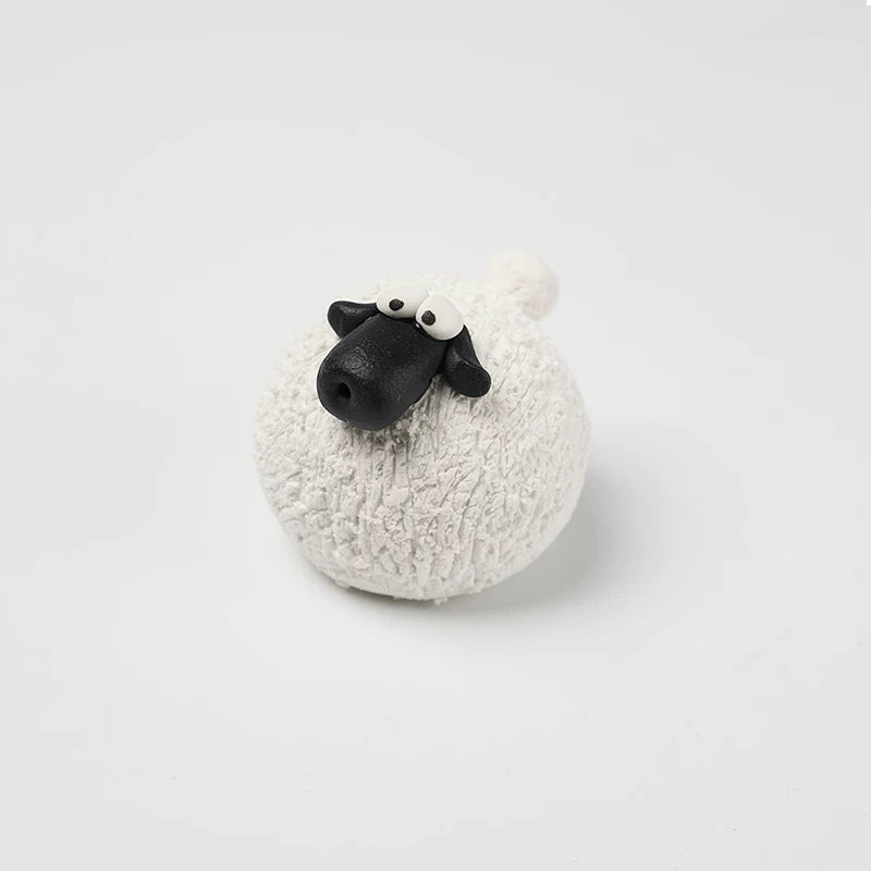 White hand-pinched pottery sheep tea pet with a black face and googly eyes