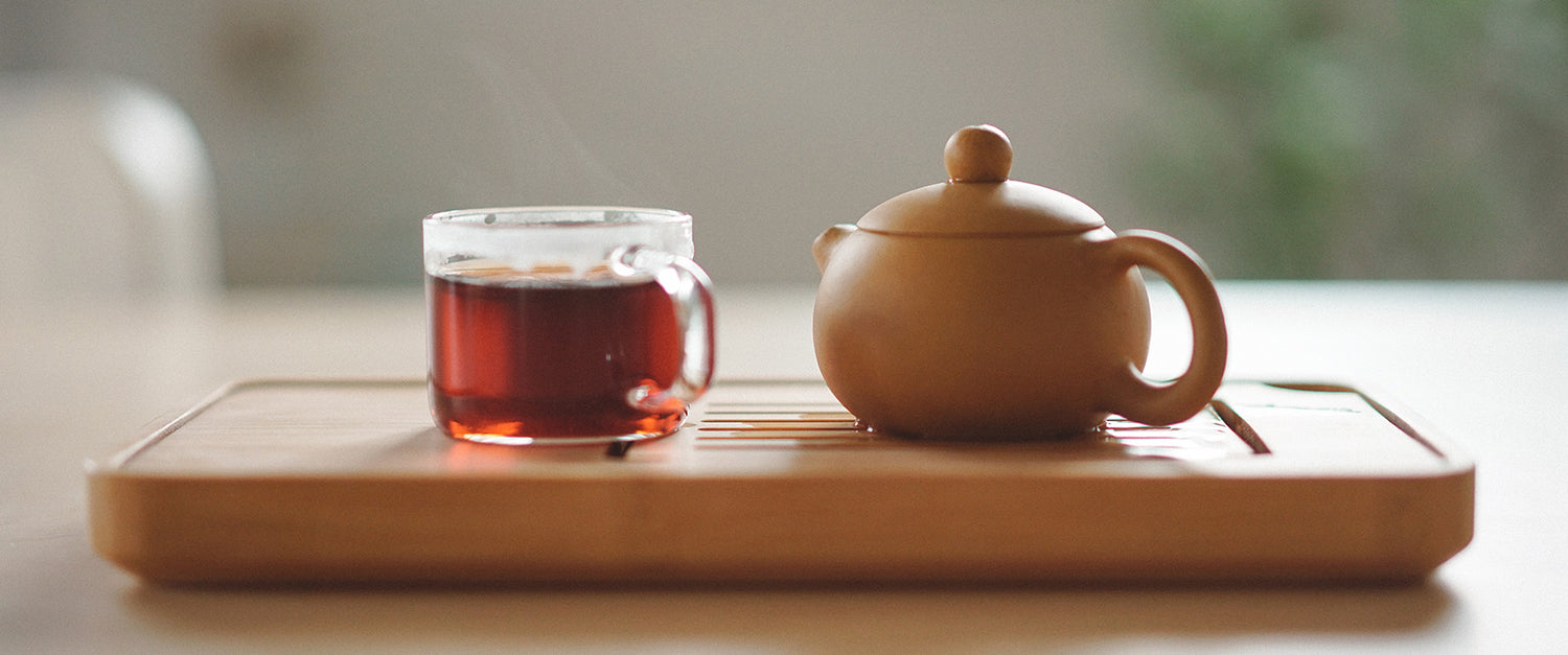 Ceramic tea pot on a wooden tray